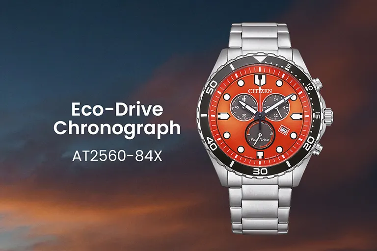 Citizen Eco-Drive Chronograph AT2560-84X mit orangefarbenem Zifferblatt und Edelstahlband vor Abendhimmel.